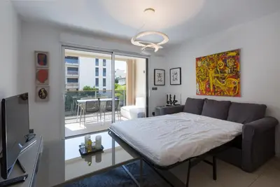 a bedroom with a bed and a living room at 2 pièces avec clim, terrasse, piscine, 100m plage in Cannes