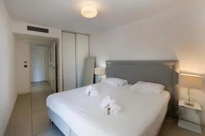 a bedroom with a large white bed with towels on it at 2 pièces avec clim, terrasse, piscine, 100m plage in Cannes