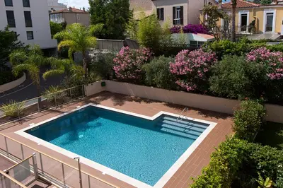 a swimming pool in the middle of a garden with flowers at 2 pièces avec clim, terrasse, piscine, 100m plage in Cannes