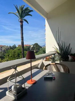 a table with a lamp on a balcony with a palm tree at Parc Montfleury in Cannes