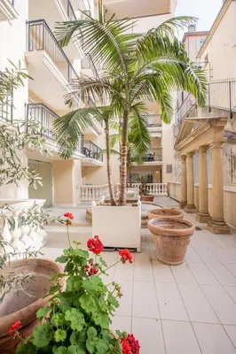 a courtyard with a palm tree in a building at Luxueux 3p. Art Deco + Parking in Cannes