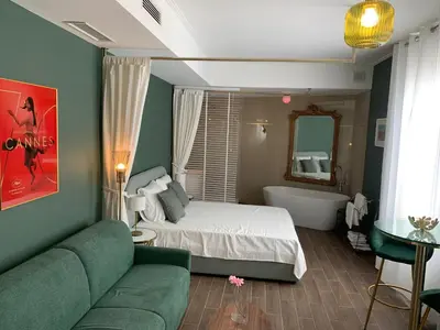 a bedroom with a bed and a tub and a couch at Villa les fougeres suite festival jardin garage in Cannes