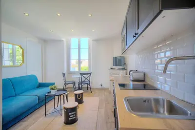 a kitchen and living room with a blue couch in a kitchen at IMMOGROOM-Suquet-AC-WIFI-close to the beaches in Cannes