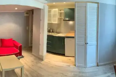 a living room with a red couch and a kitchen at Grand studio centre Cannes in Cannes