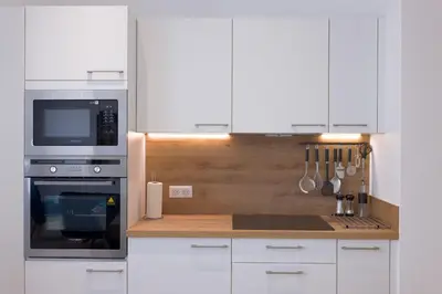 a kitchen with white cabinets and a stove and microwave at Rue De Bone by Halldis in Cannes