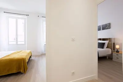 a bedroom with white walls and a bed and a mirror at Rue De Bone by Halldis in Cannes