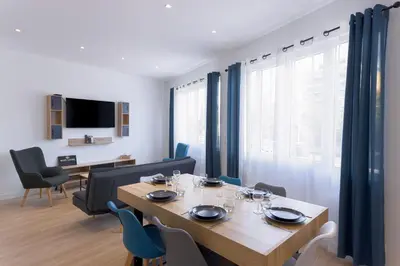 a dining room with a wooden table and blue chairs at Rue De Bone by Halldis in Cannes