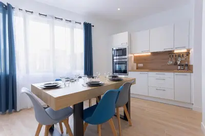 a kitchen with a wooden table and blue chairs at Rue De Bone by Halldis in Cannes